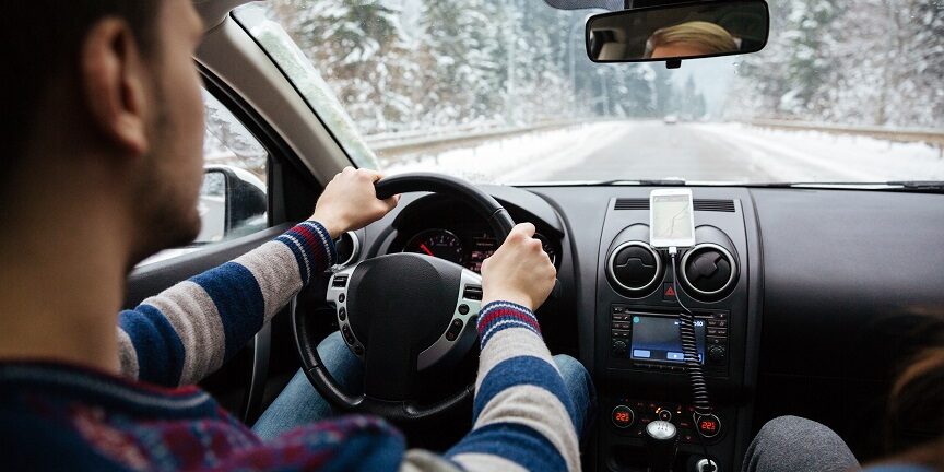 Handsome young driver driving through winter forest